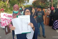Warga menunjukkan dokumen tanda tangan yang diduga tidak mereka tandatangani saat aksi penolakan tambang. (Foto: Redaksiku.com)