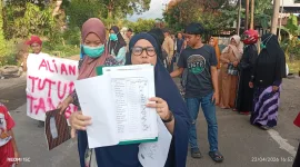 Warga menunjukkan dokumen tanda tangan yang diduga tidak mereka tandatangani saat aksi penolakan tambang. (Foto: Redaksiku.com)