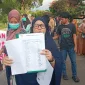 Warga menunjukkan dokumen tanda tangan yang diduga tidak mereka tandatangani saat aksi penolakan tambang. (Foto: Redaksiku.com)