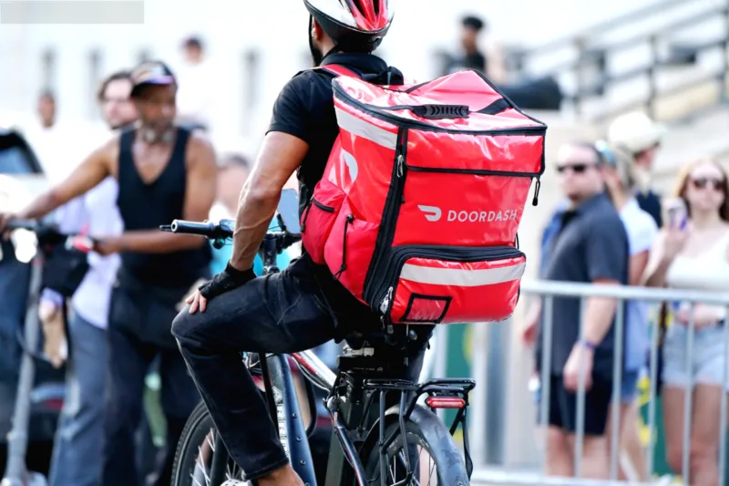 Kurir pengantar makanan DoorDash mengendarai sepeda di jalanan New York City.