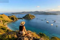 Destinasi Wisata Menarik — Pemandangan lanskap pesisir dan laut biru di Labuan Bajo dengan perbukitan hijau di sekitarnya.