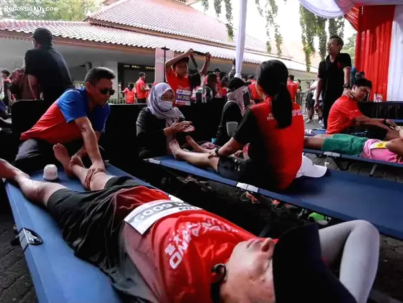 Seorang terapis tunanetra memberikan layanan pijat pemulihan otot kepada pelari di ajang Soekarno Run Banyuwangi.