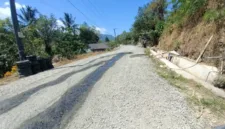 Foto : redaksiku.com. Debu menyelimuti Jalan Doi-Doi–Wanawaru–Barang hingga warga harus menyiramnya setiap hari.