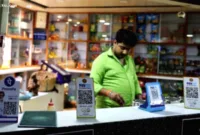 Dampak Aturan Pembayaran — Seorang pelanggan memindai kode QR untuk pembayaran digital di restoran India.