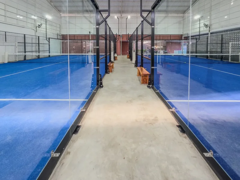 Tren Olahraga Padel — Pemain padel beraksi di lapangan profesional dengan dinding kaca modern