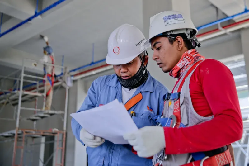 Pekerja membaca dokumen kontrak kerja dengan teliti sebelum menandatanganinya.