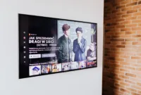 Logo JustWatch TV pada layar televisi pintar dengan latar belakang antarmuka aplikasi streaming.